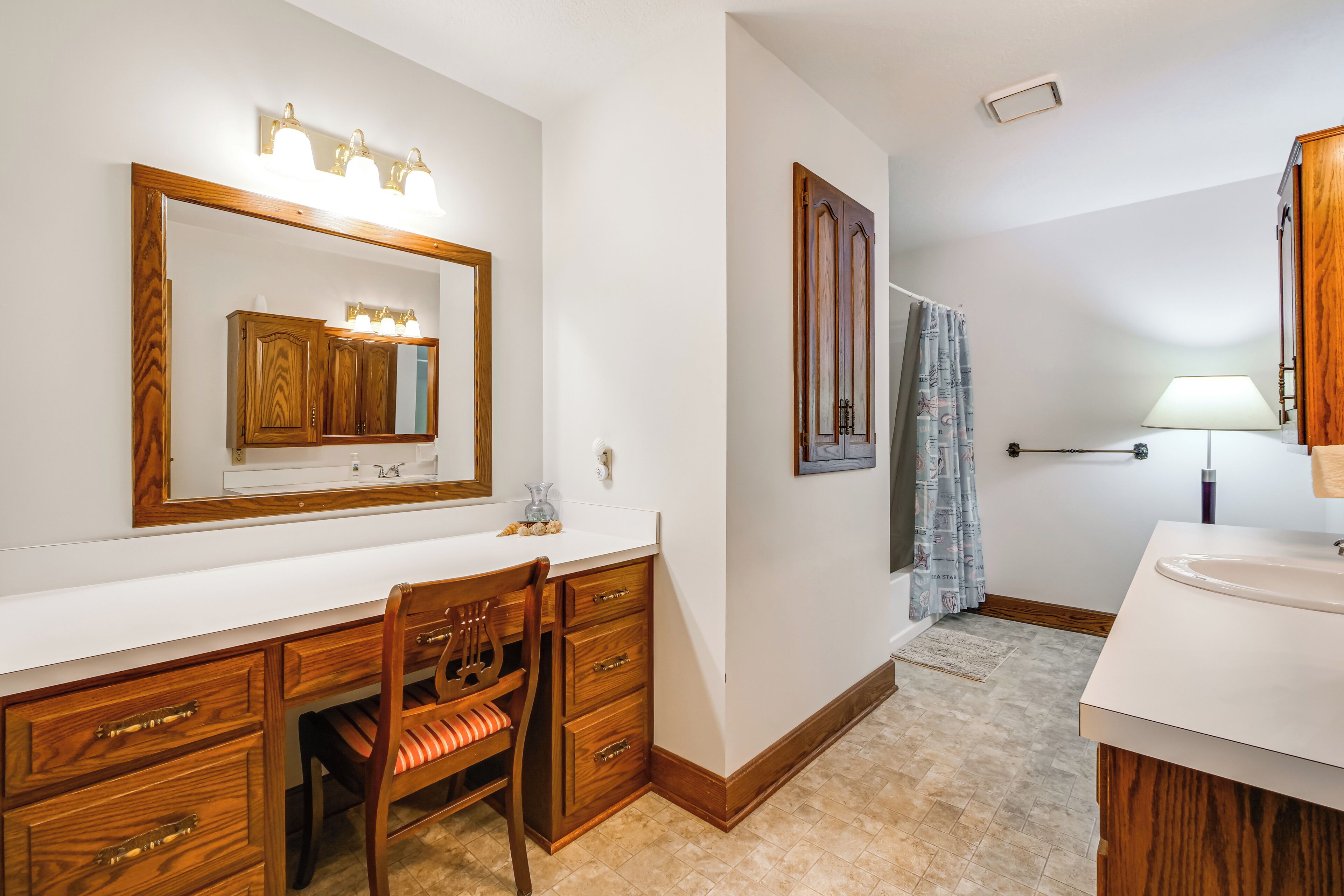 A bathroom with a wooden vanity, a mirror, and a shower area.