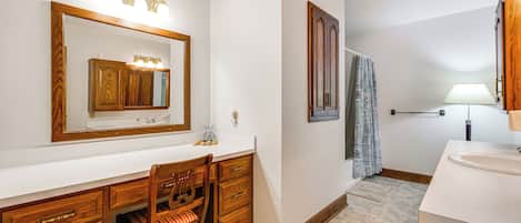 A bathroom with a wooden vanity, a mirror, and a shower area.