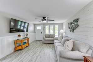 A living room with a ceiling fan, a television mounted on the wall, a sofa, a coffee table, and a door leading to another room. - 2 Blocks to Beach: Tropical Retreat in Anna Maria (Anna Maria)
