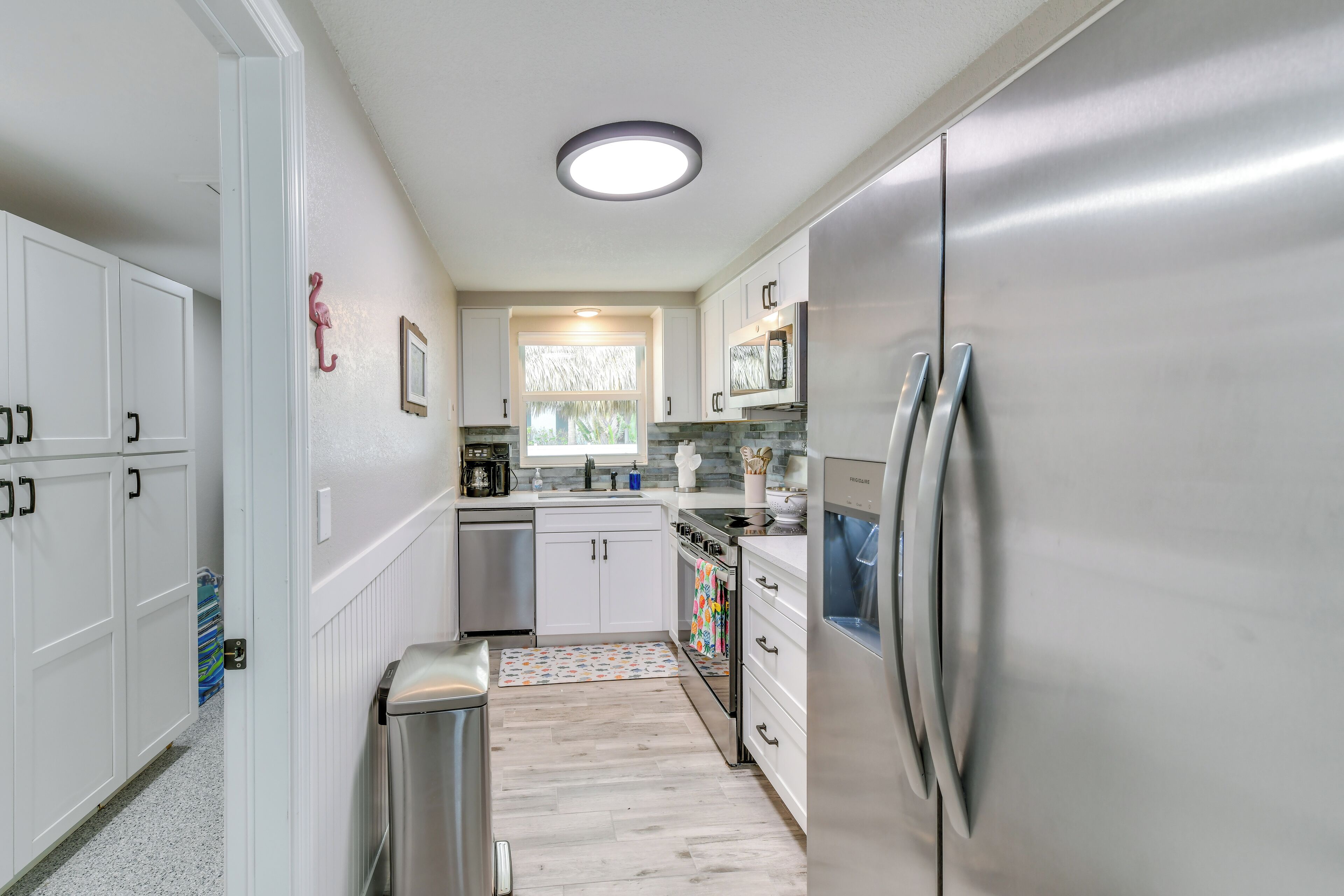 A modern kitchen with white cabinetry, stainless steel appliances, and a window providing natural light.