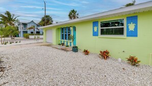A building with a green exterior, blue windows, and a small garden area with plants. - 2 Blocks to Beach: Tropical Retreat in Anna Maria (Anna Maria)