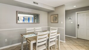 Zona pranzo con tavolo in legno e quattro sedie, uno specchio grande e un elemento decorativo al muro.
