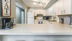 Una cucina moderna con mobili bianchi, un frigorifero, un fornello e una macchina da caffè.