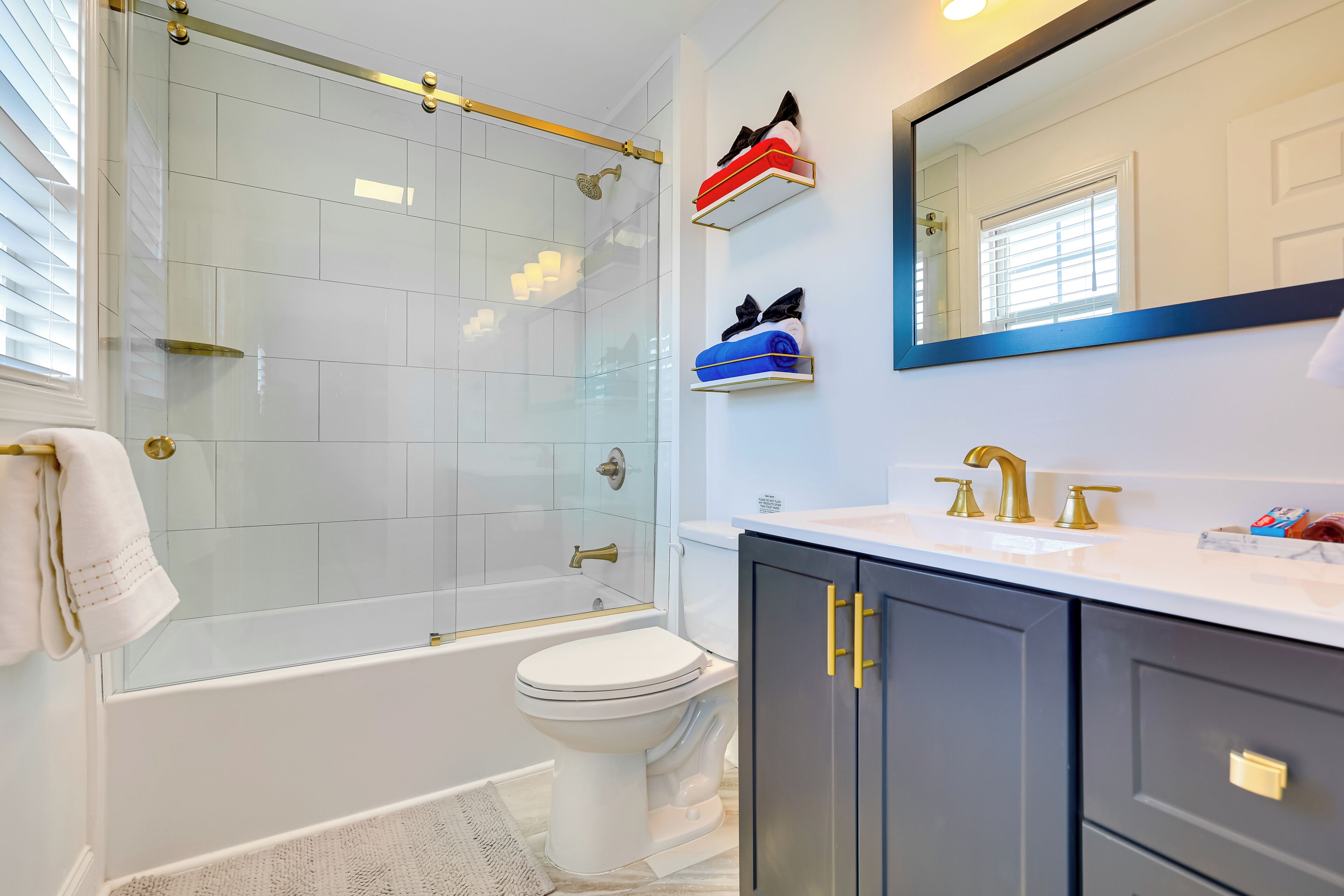 A modern bathroom with a glass shower enclosure, a white toilet, and a vanity with a mirror.