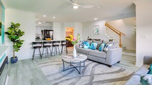 A modern living room with a grey sofa, a marble coffee table, and a staircase leading to an upper level. - Walk to Ocean: Carolina Beach Condo w/ 2 Balconies (Carolina Beach)