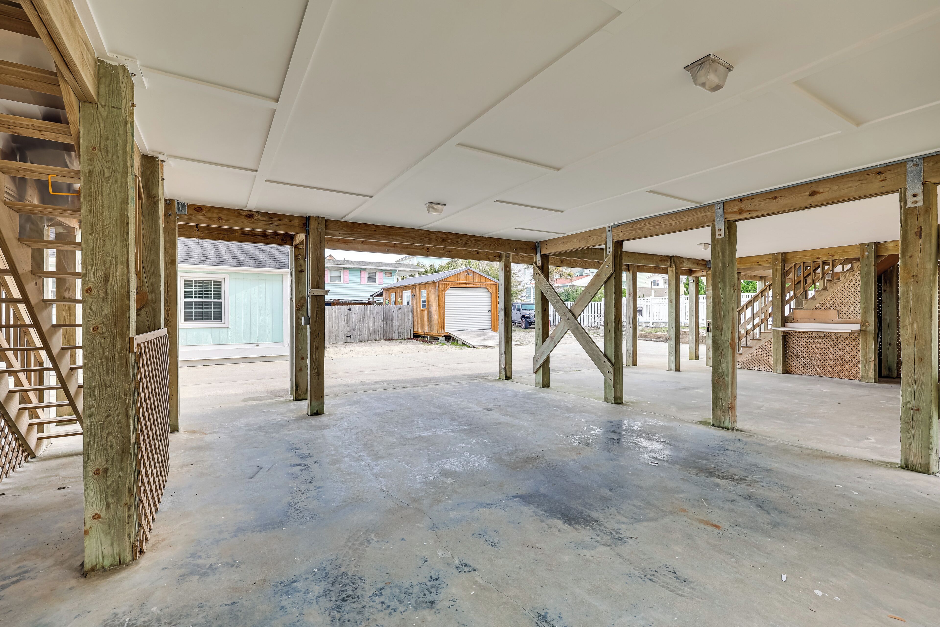 An open, unfinished interior space with exposed wooden beams and a concrete floor.