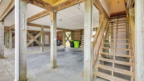 An open garage with exposed wooden beams and a concrete floor. - Walk to Ocean: Carolina Beach Condo w/ 2 Balconies (Carolina Beach)