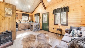 A cabin interior with a wooden interior, a fireplace, a sofa, and a dining area. - 'bluebird Treehouse' Near Kiamichi Mtns w/ Hot Tub (Talihina)