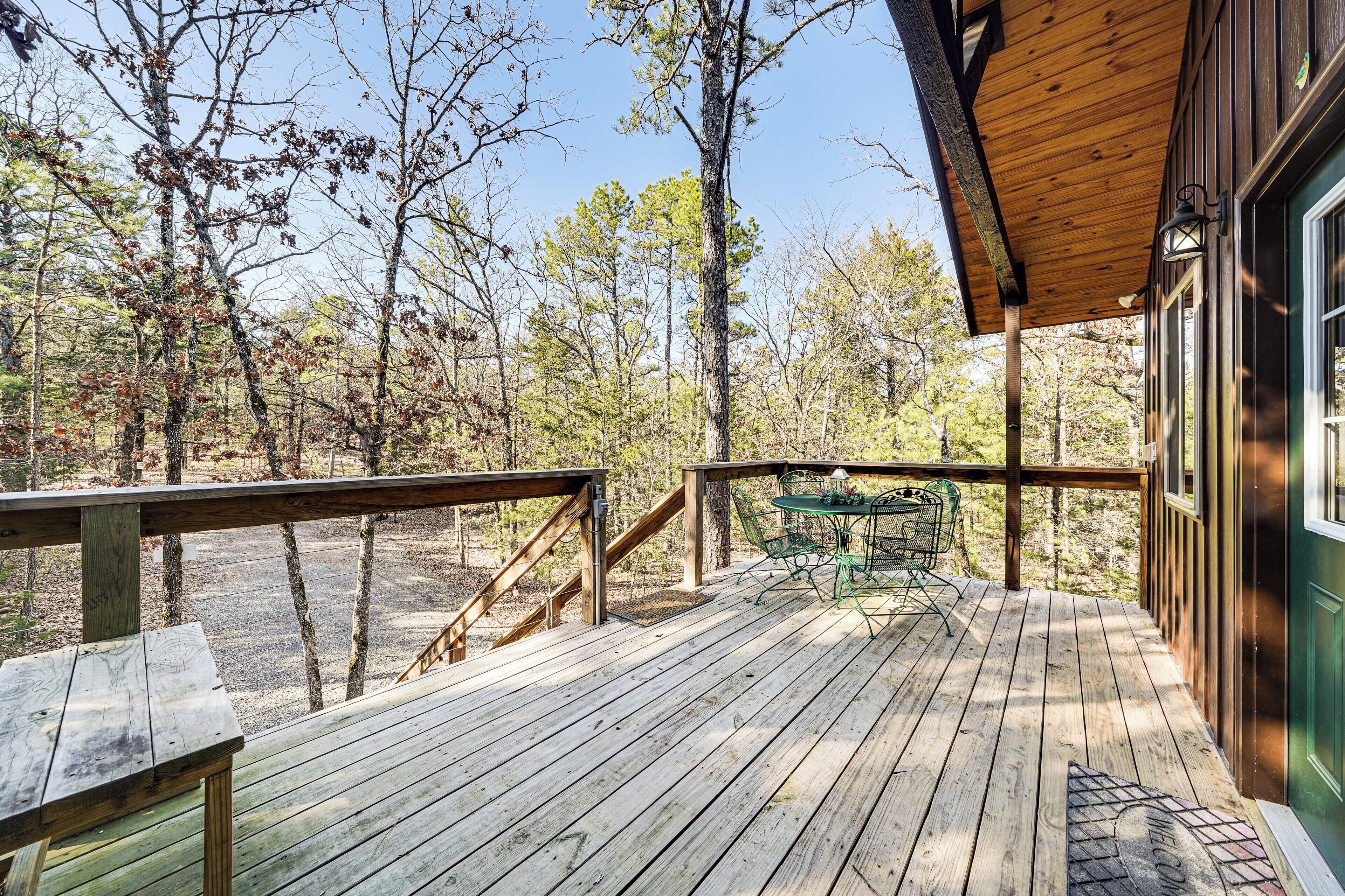 A wooden deck with a table and chairs, surrounded by trees.