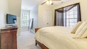 A bedroom with a bed, a ceiling fan, a television on a dresser, and a window with curtains. - Hike, Golf & Boat: Wake Forest Home w/ Yard (Wake Forest)