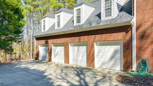 A two-story house with a brick exterior and white garage doors. - Hike, Golf & Boat: Wake Forest Home w/ Yard (Wake Forest)