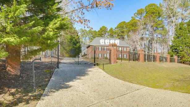 A brick building with a gated entrance, surrounded by trees and a paved pathway. - Hike, Golf & Boat: Wake Forest Home w/ Yard (Wake Forest)