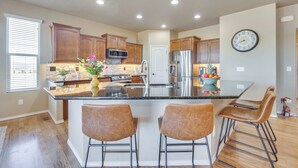 Una cocina moderna con armarios de madera, electrodomésticos de acero inoxidable y una isla central con taburetes de bar.