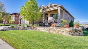 Una casa de dos pisos con base de piedra y un porche cubierto.