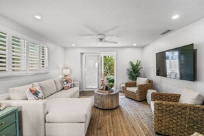 A modern living room with a sofa, armchairs, a coffee table, and a television.
