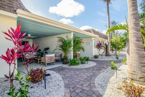 A covered outdoor seating area with a patio, potted plants, and a pathway.