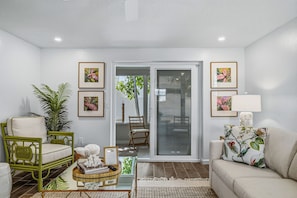 A living room with a sofa, chairs, a coffee table, and a sliding glass door leading to an outdoor area.