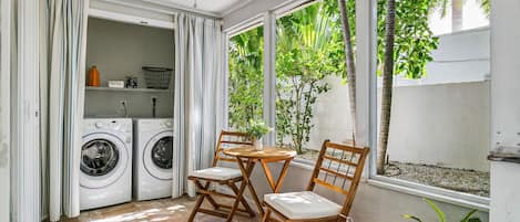 A laundry area with two washing machines, a table with chairs, and a ceiling fan.