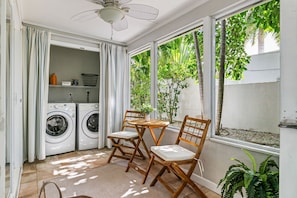A laundry area with two washing machines, a table with chairs, and a ceiling fan.