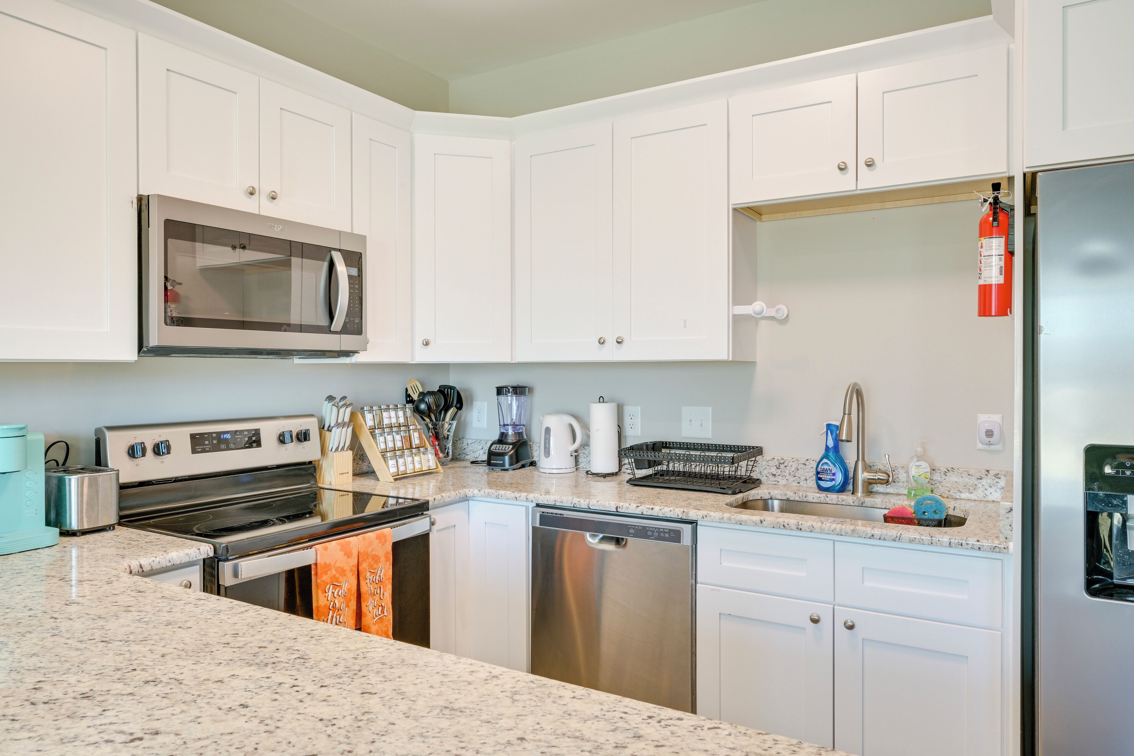 A modern kitchen with white cabinets, stainless steel appliances, and granite countertops.