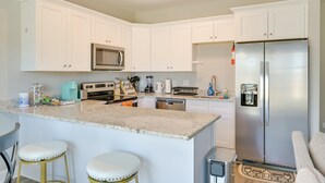 A kitchen with white cabinets, a stainless steel refrigerator, a microwave, and a granite countertop. - Stay & Play: Spacious Concord Townhome Near Uptown (Concord)