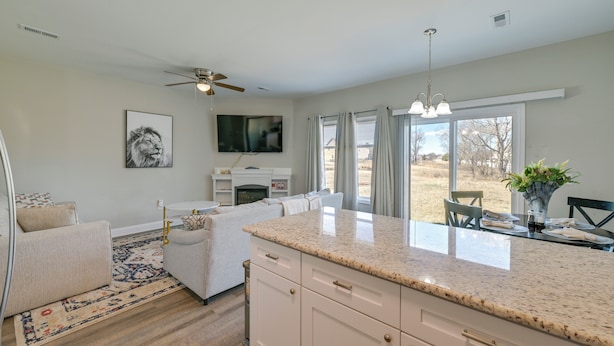 A modern kitchen with a granite countertop, white cabinetry, and a dining area with a table and chairs. - Stay & Play: Spacious Concord Townhome Near Uptown (Concord)