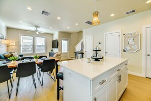 A modern kitchen with a central island, dining area with chairs, and a living space with a sofa and TV. - 1 Mi to Beach: Home w/ Pool Access in Port Aransas (Port Aransas)