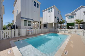 A rectangular pool with a white fence and palm trees, surrounded by white buildings with a beach house style. - 1 Mi to Beach: Home w/ Pool Access in Port Aransas (Port Aransas)