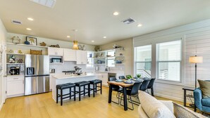 A modern kitchen with white cabinets, stainless steel appliances, and a central island with bar stools. - 1 Mi to Beach: Home w/ Pool Access in Port Aransas (Port Aransas)