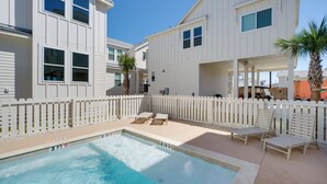 A pool area with lounge chairs and a white fence. - 1 Mi to Beach: Home w/ Pool Access in Port Aransas (Port Aransas)