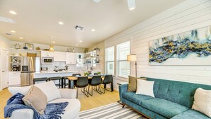 A modern kitchen with white cabinets, a stainless steel refrigerator, and a dining area with a table and chairs. - 1 Mi to Beach: Home w/ Pool Access in Port Aransas (Port Aransas)