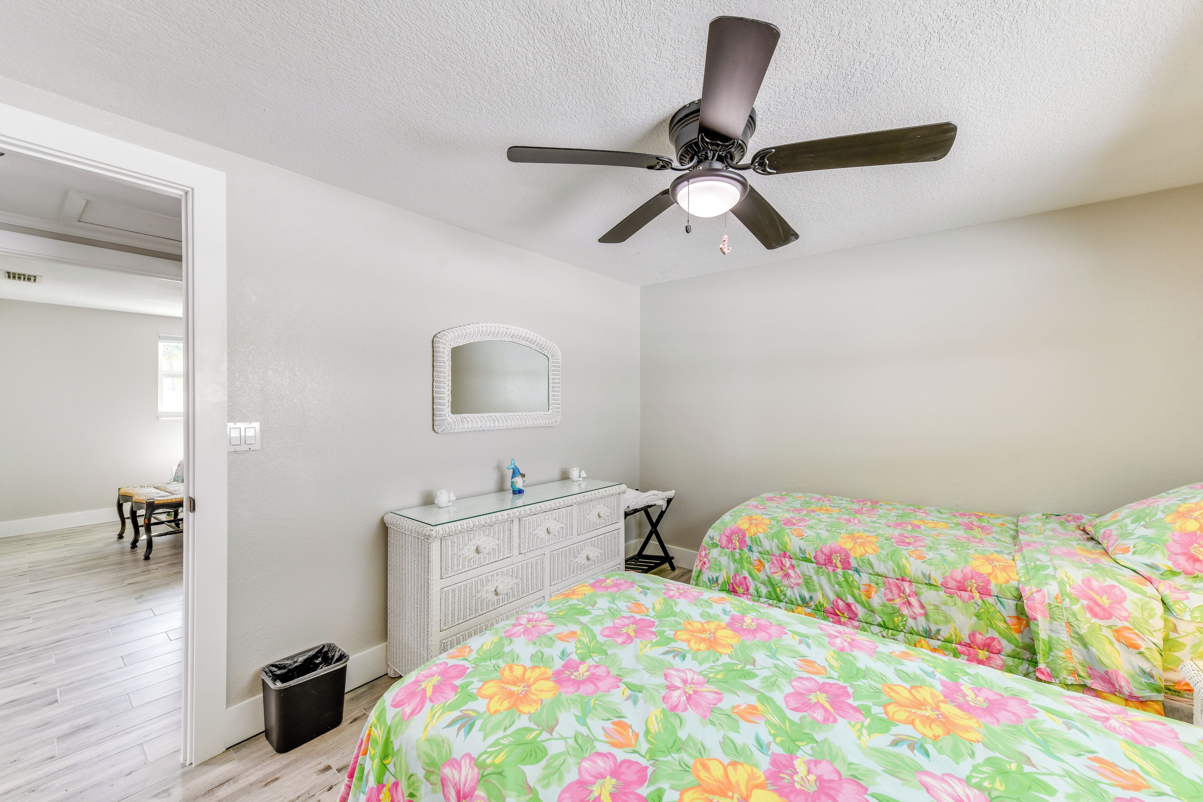 A bedroom with two beds, a ceiling fan, a dresser, and a mirror.