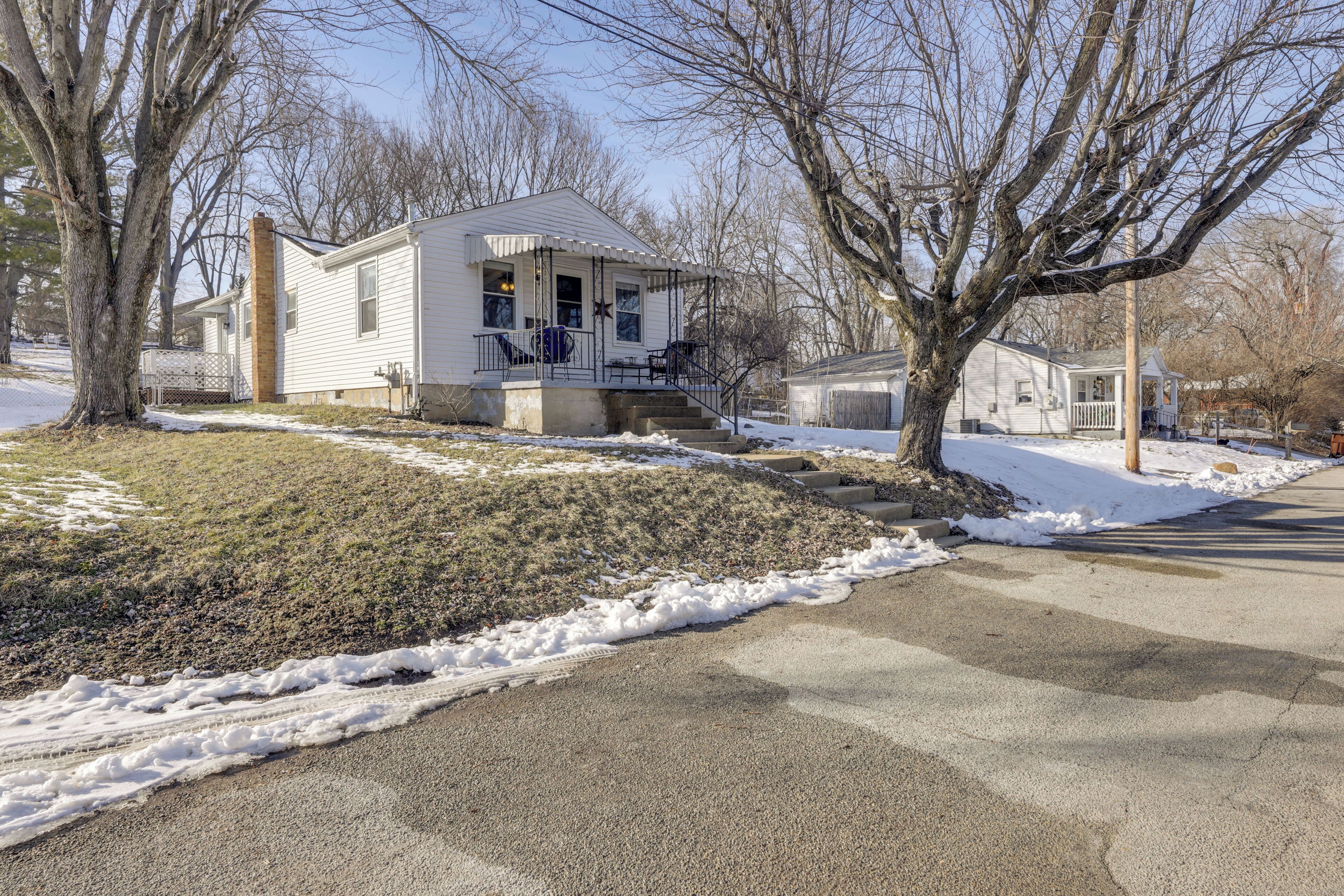 A single-story house with a front porch, a visible garage, and a snow-covered yard.
