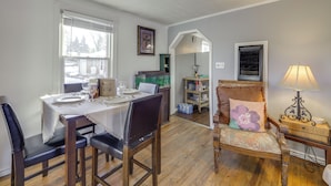 A dining area with a table set for four, a wooden chair, a cushioned chair with a floral pillow, and a side table with a lamp. - 3 Mi to Englewood Dam: Pet-friendly Home w/ Yard! (Englewood)