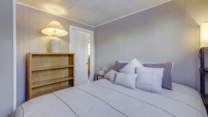 A bedroom with a large bed, a wooden bookshelf, a nightstand with a lamp, and a door leading to another room. - 3 Mi to Englewood Dam: Pet-friendly Home w/ Yard! (Englewood)