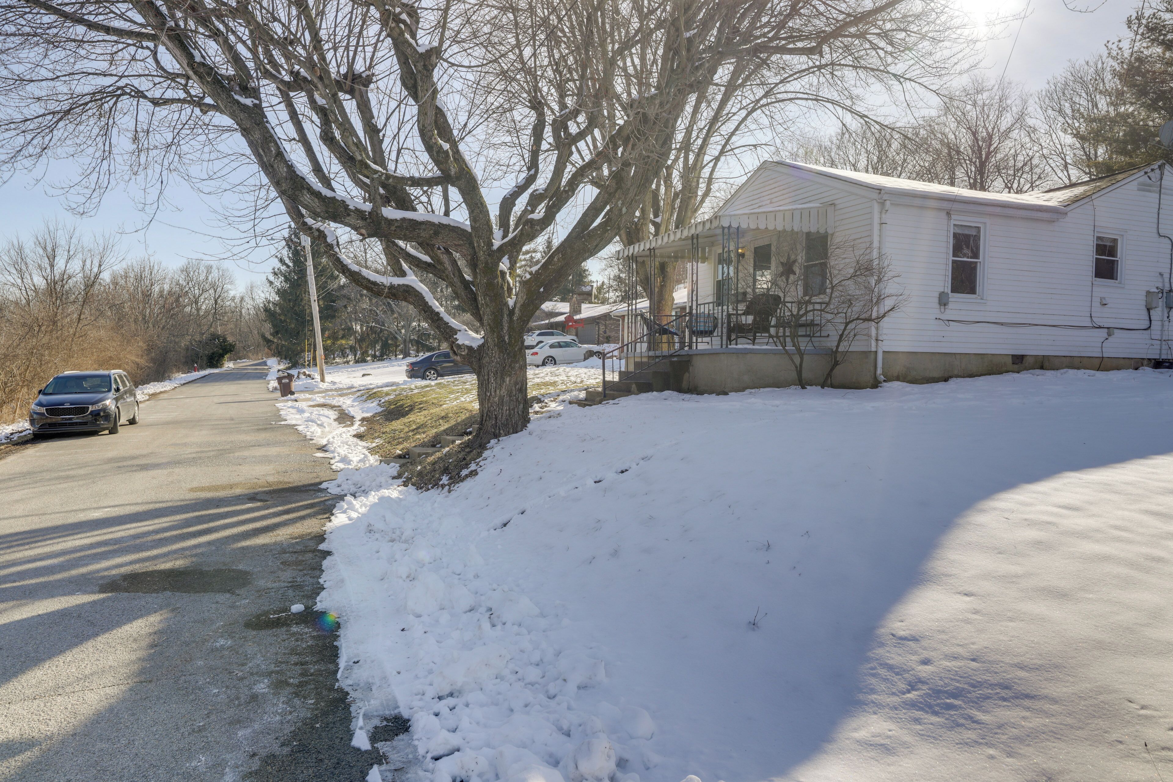 A residential house with a porch, a driveway, and a snow-covered yard.