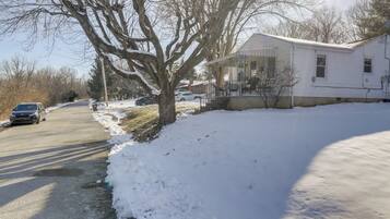 A residential house with a porch, a driveway, and a snow-covered yard.