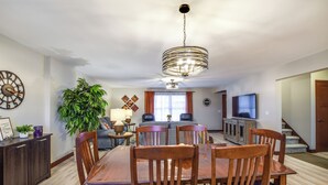 A dining area with a wooden table and chairs, a chandelier, and a large potted plant. - 2026-NEW BOOKING SPECIAL at The Belvedere just Steps to downtown. (New Glarus)