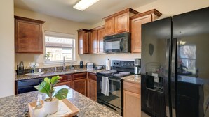A kitchen with wooden cabinets, a black refrigerator, a microwave, a stove, and granite countertops. - Suburban Home in Magnolia w/ Fenced Yard (Magnolia)