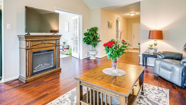 A spacious living room with hardwood flooring, a fireplace, a television, a dining table, and a leather sofa. - Suburban Home in Magnolia w/ Fenced Yard (Magnolia)