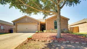 A two-story brick house with a garage, a front yard with a tree, and a well-maintained lawn. - Suburban Home in Magnolia w/ Fenced Yard (Magnolia)