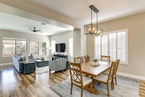 Relax in this spacious living room with a high ceiling, featuring a large window, flat-screen TV, and comfortable seating area.