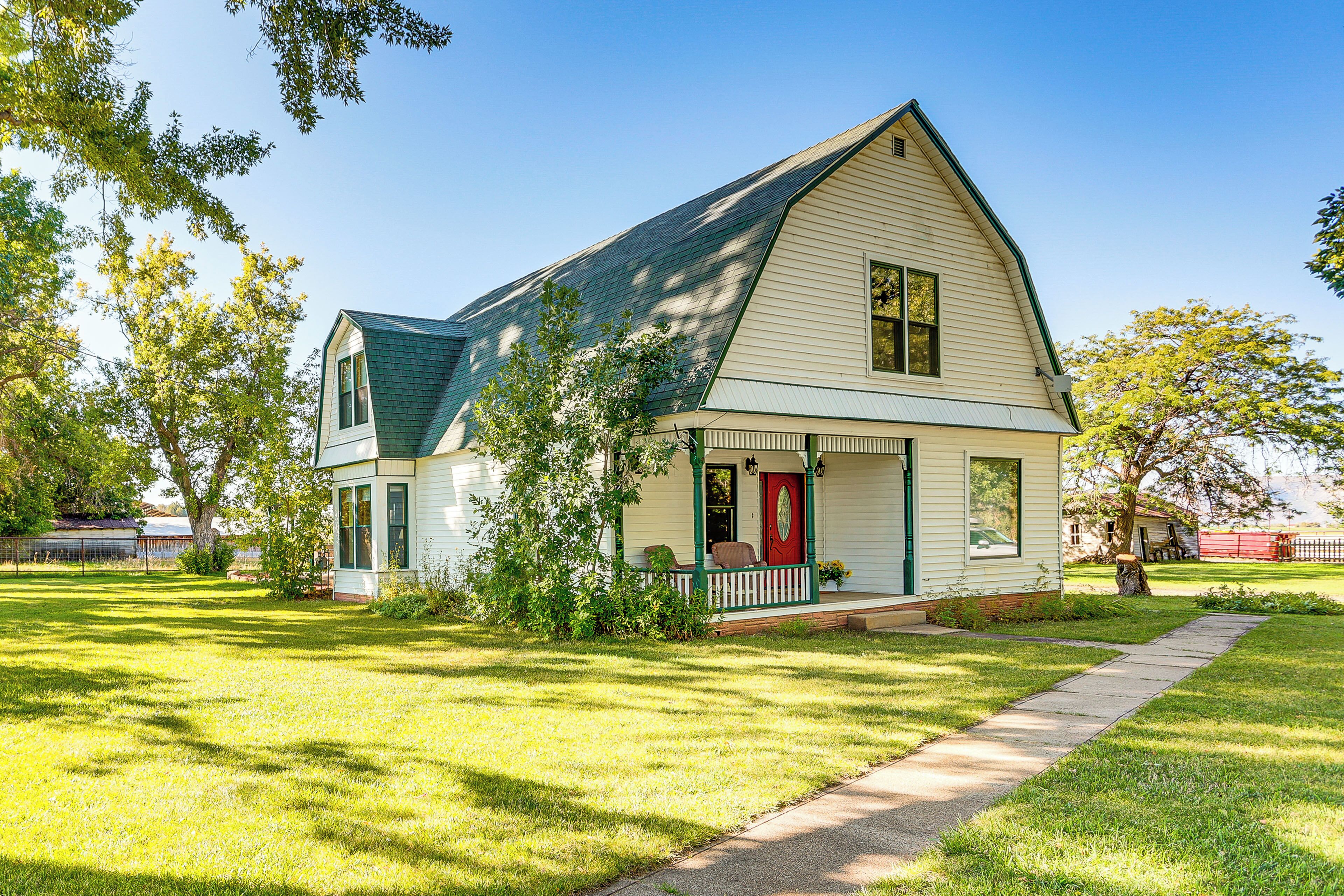 A single-story house with a green roof, a red front door, and a front porch.