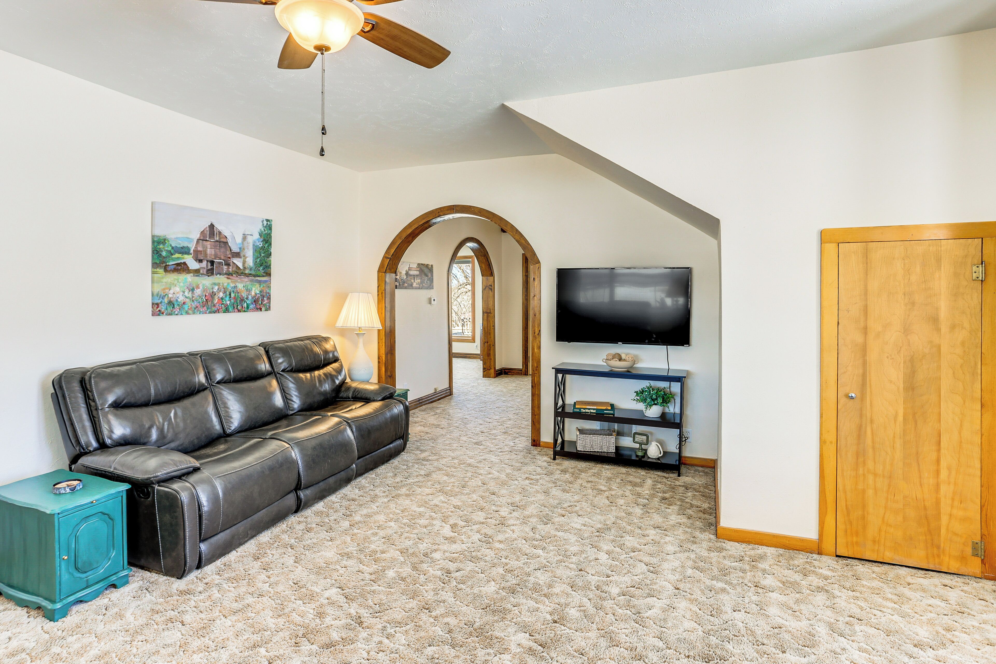 A living room with a leather sofa, a TV, and a wooden door.