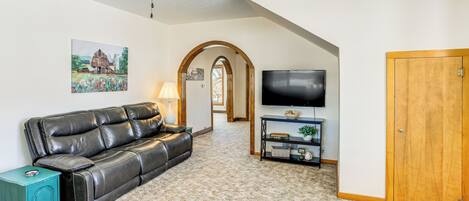 A living room with a leather sofa, a TV, and a wooden door.