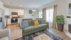 Ein modernes Wohnzimmer mit einer Couch, einem Couchtisch und einem Kamin. Es gibt eine Küchenzeile mit einer Mikrowelle und einem Backofen.