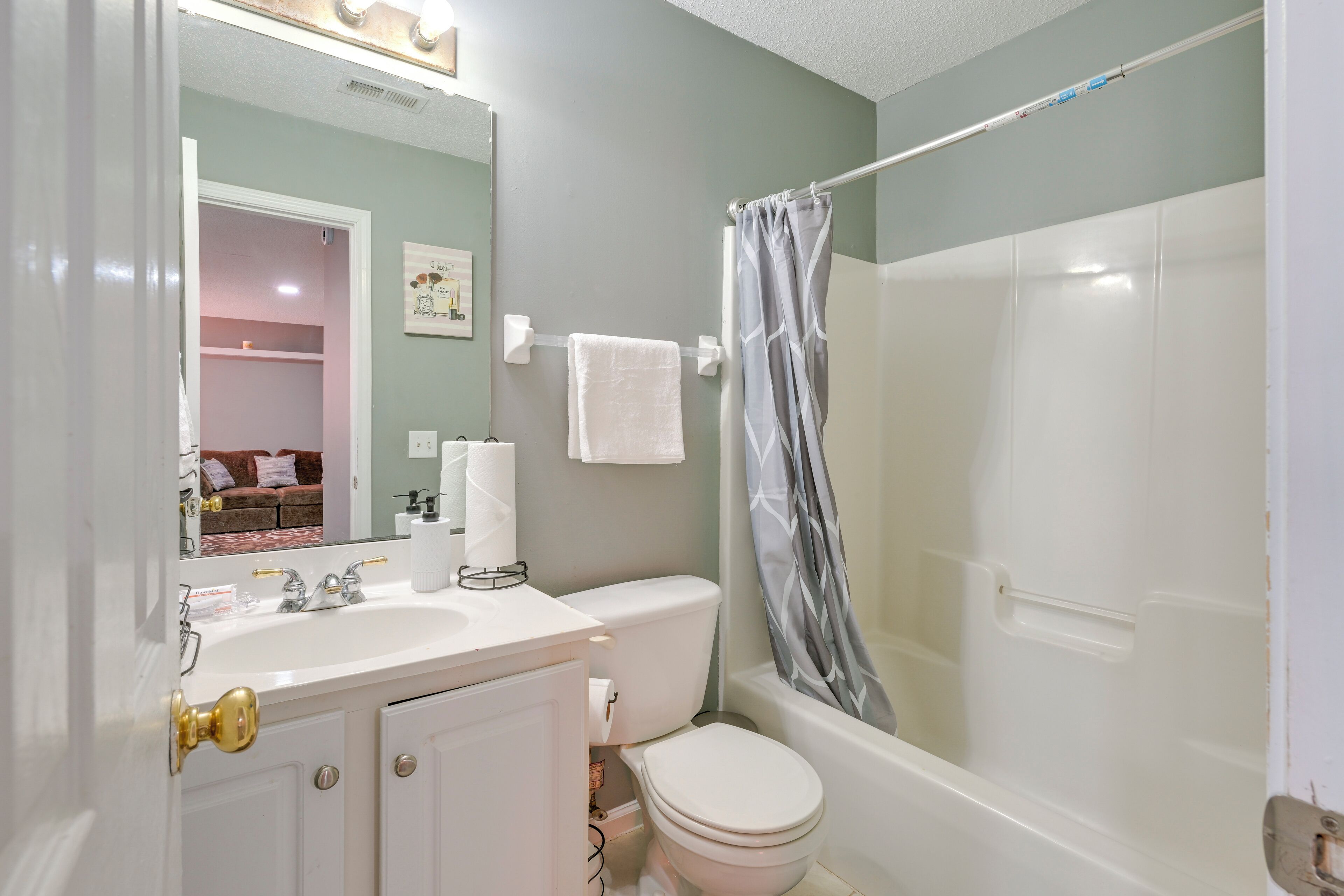 A bathroom with a white sink, toilet, and bathtub. There is a shower curtain and a towel hanging on the wall.