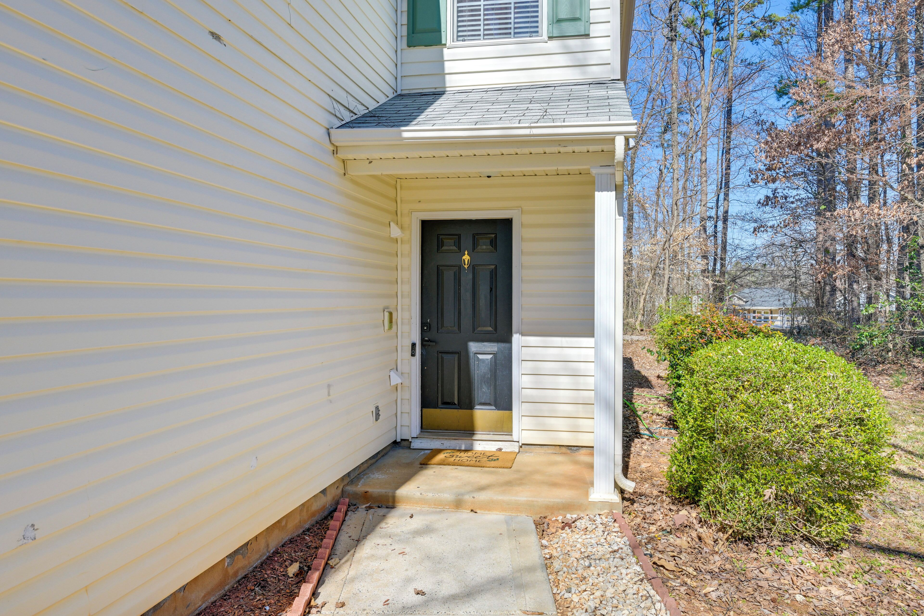 A house with a front door, a small porch, and a front yard with a bush.
