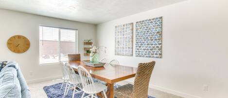 A dining area with a wooden table, white chairs, and a blue rug.
