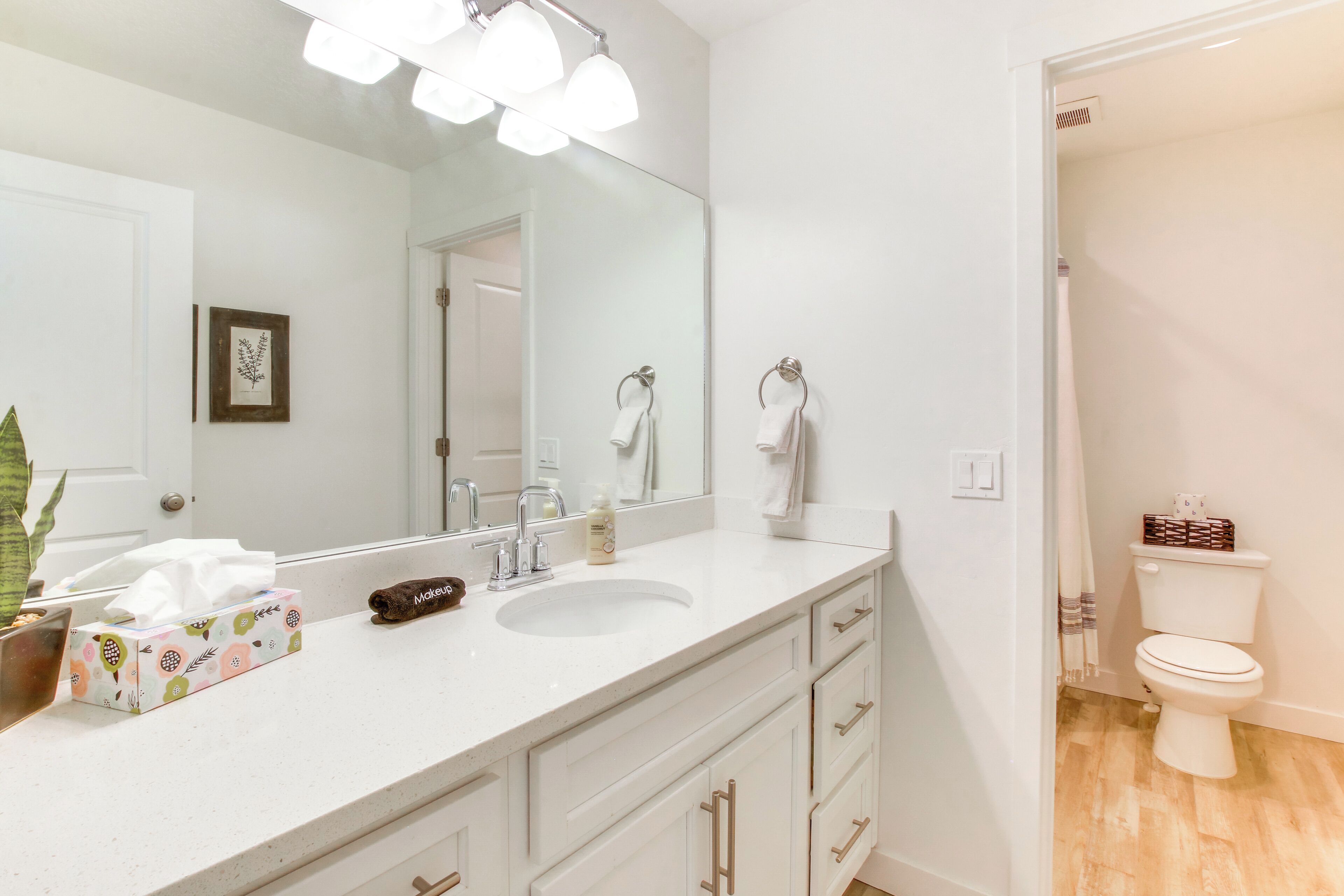 A modern bathroom with a white sink, a large mirror, and a toilet.
